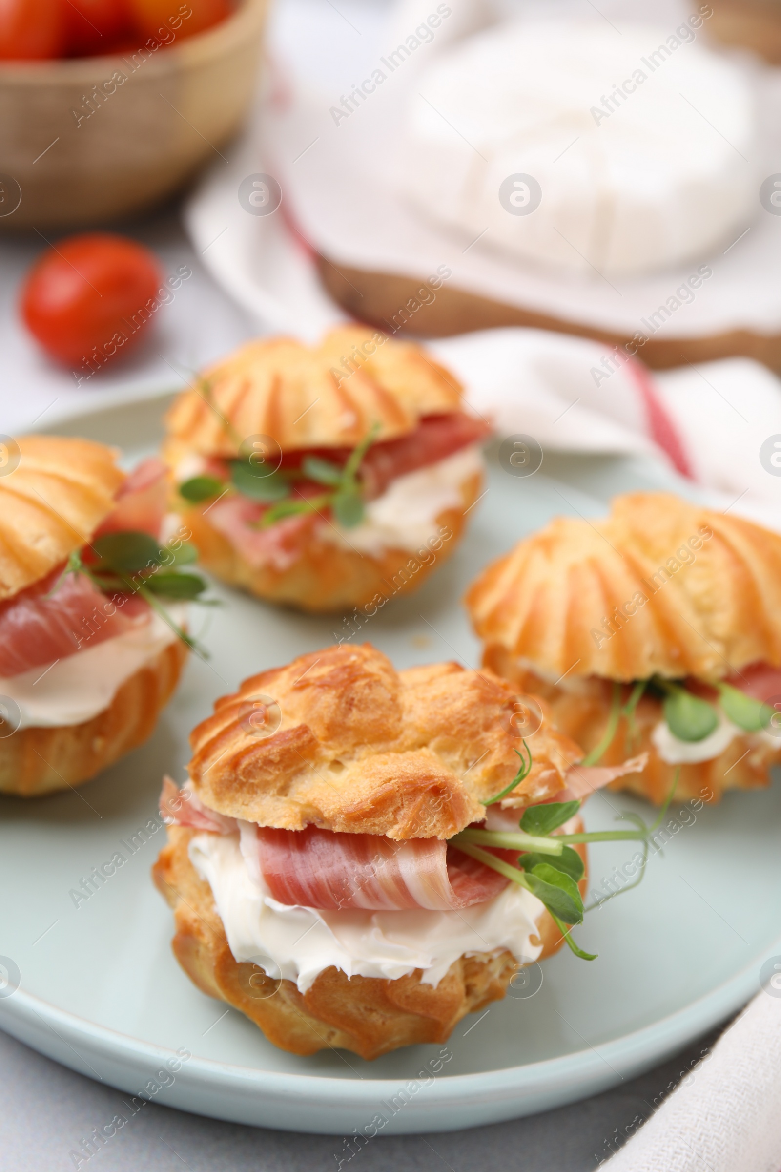 Photo of Delicious profiteroles with cream cheese and prosciutto on plate, closeup