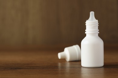 Bottle of nasal spray and cap on wooden table, space for text
