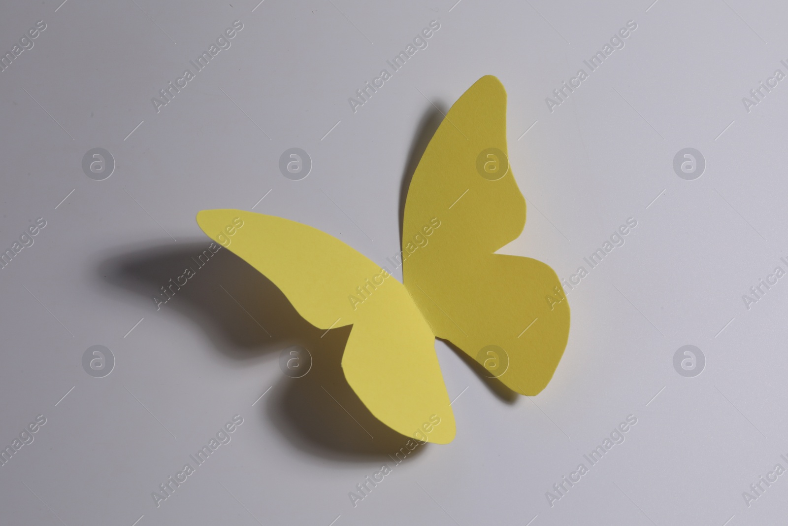 Photo of Yellow paper butterfly on light background, top view