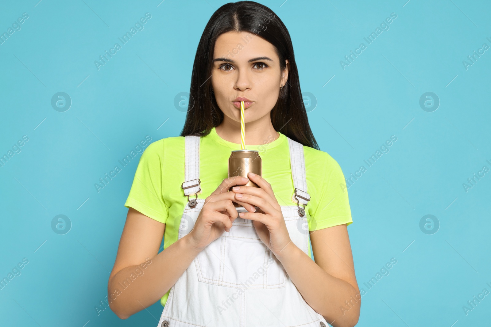 Photo of Beautiful woman drinking from beverage can on light blue background