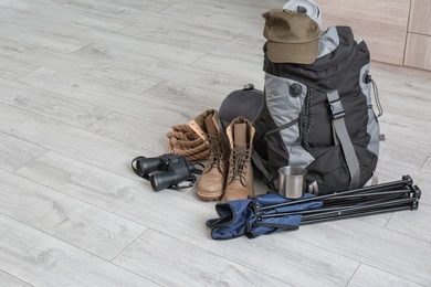 Photo of Set of camping equipment with sleeping bag on wooden floor. Space for text