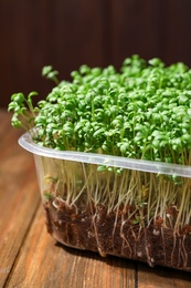 Photo of Fresh organic microgreen on wooden table, closeup