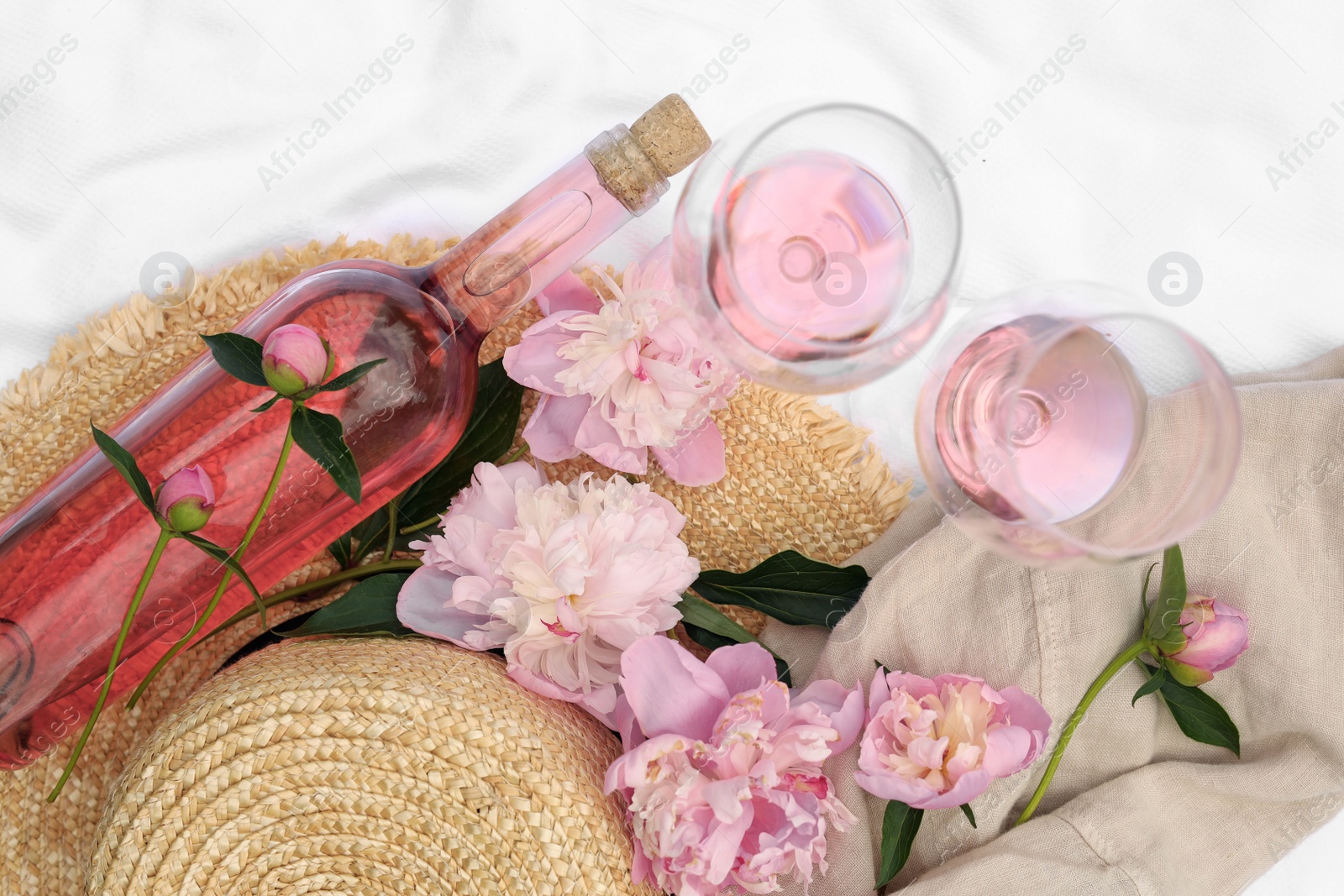 Photo of Flat lay composition with beautiful peonies and rose wine on white fabric