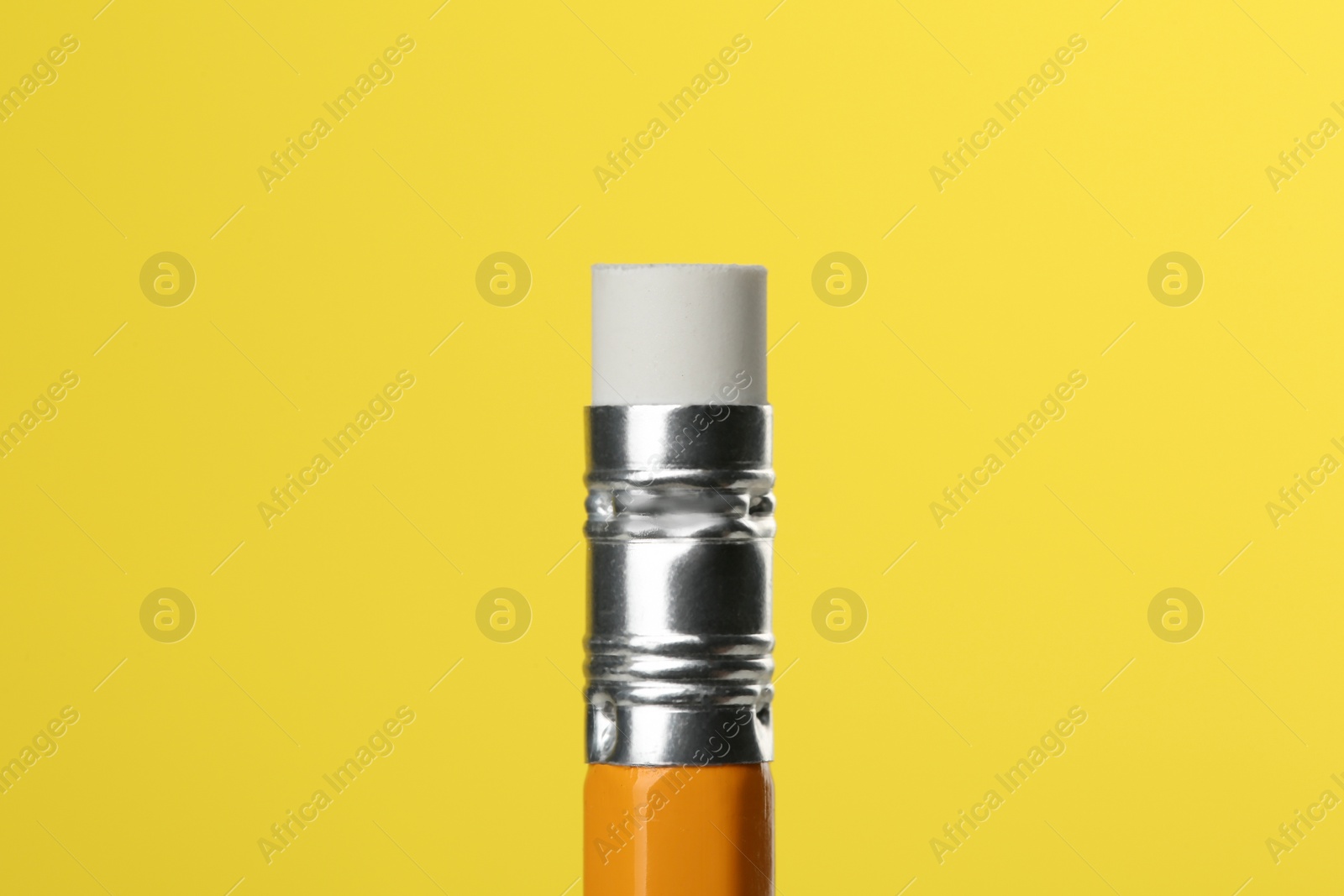 Photo of Graphite pencil with eraser on yellow background, macro view