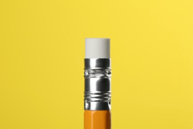 Photo of Graphite pencil with eraser on yellow background, macro view