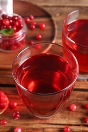 Photo of Tasty cranberry juice in glasses and fresh berries on wooden table, closeup