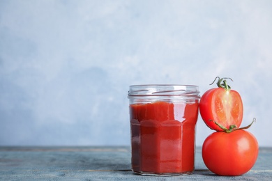 Photo of Jar with homemade tomato sauce and fresh vegetables on light background. Space for text