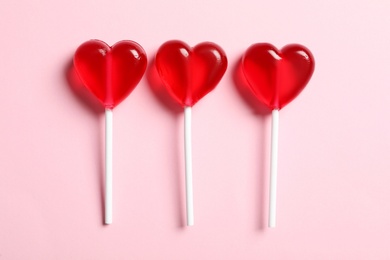 Photo of Sweet heart shaped lollipops on pink background, flat lay. Valentine's day celebration
