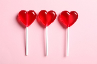 Sweet heart shaped lollipops on pink background, flat lay. Valentine's day celebration