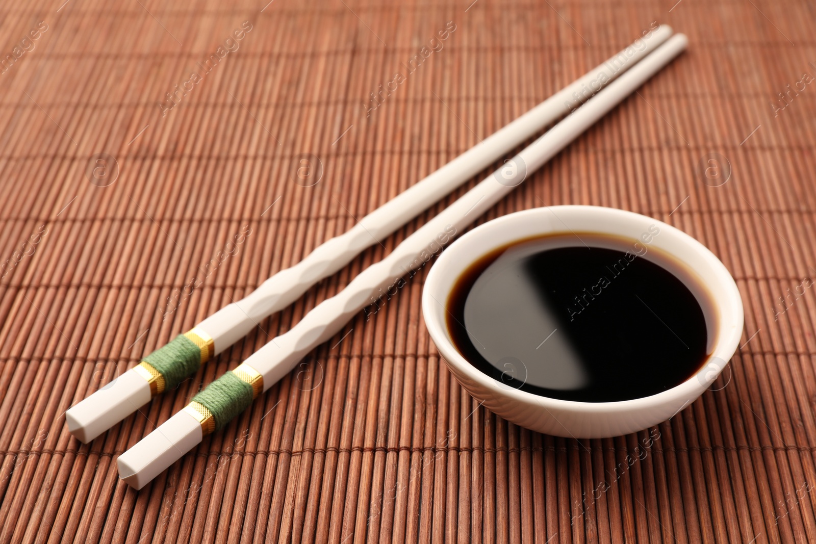 Photo of Bowl of soy sauce and chopsticks on bamboo mat