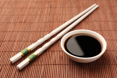 Bowl of soy sauce and chopsticks on bamboo mat