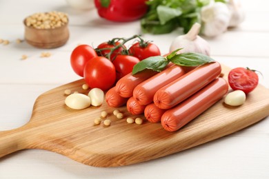 Photo of Fresh raw vegetarian sausages and vegetables on white wooden table