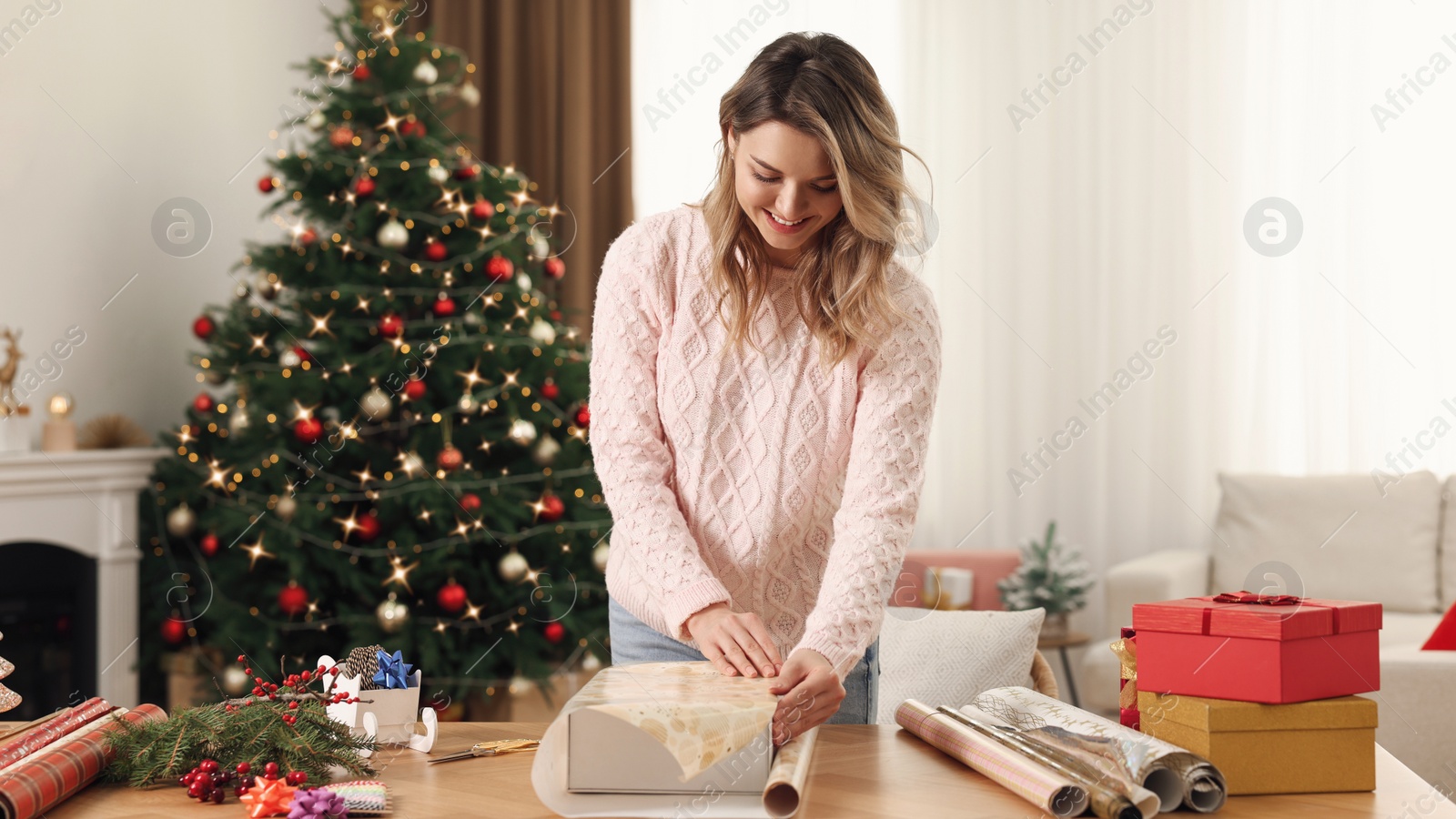 Photo of Beautiful young woman wrapping Christmas gift at home