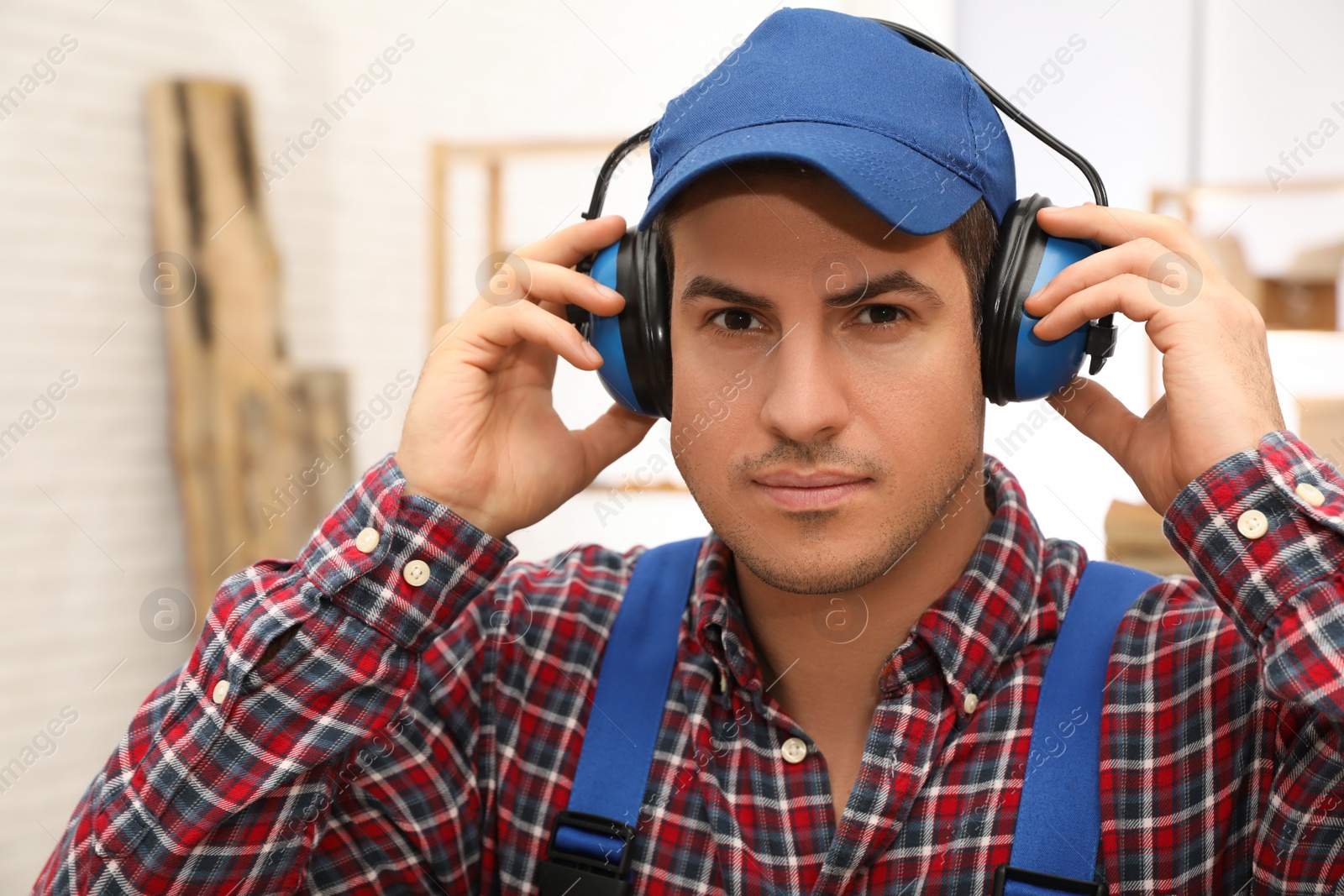 Photo of Worker wearing safety headphones indoors. Hearing protection device