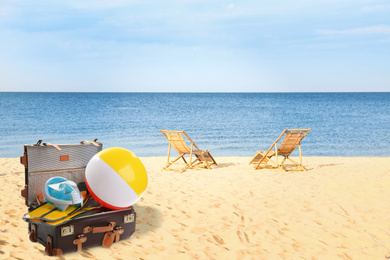 Image of Suitcase with different beach objects on sand near sea