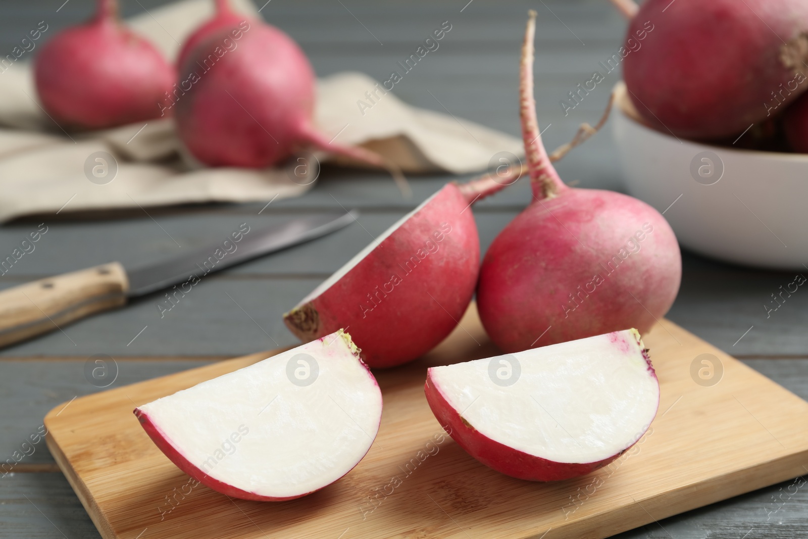 Photo of Red cut and whole turnips on grey wooden table, closeup