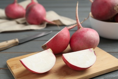 Photo of Red cut and whole turnips on grey wooden table, closeup