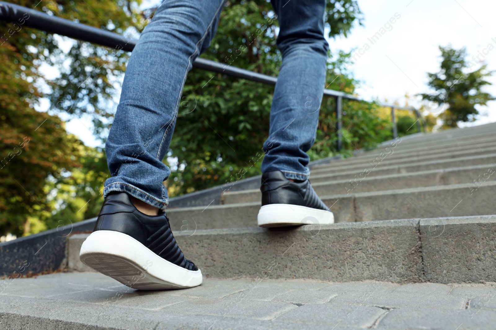 Photo of Man in stylish black sneakers walking up stairs, closeup