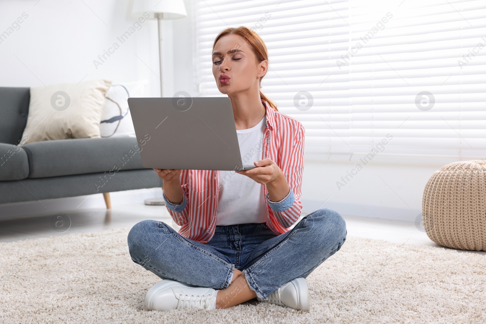 Photo of Woman blowing kiss during video chat via laptop at home. Long-distance relationship