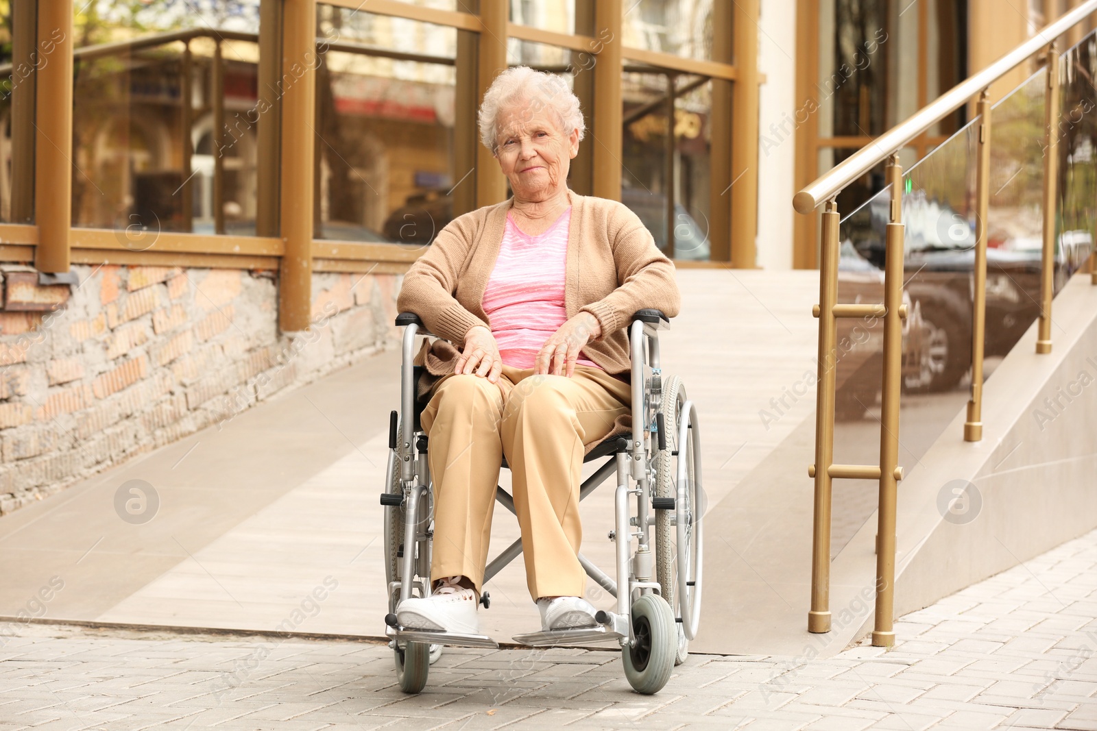 Photo of Happy senior woman in wheelchair at ramp outdoors