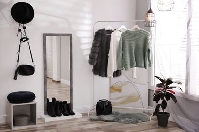 Photo of Stylish warm clothes on rack in dressing room interior