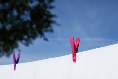 Photo of Laundry with clothes pins on line outdoors, closeup. Space for text