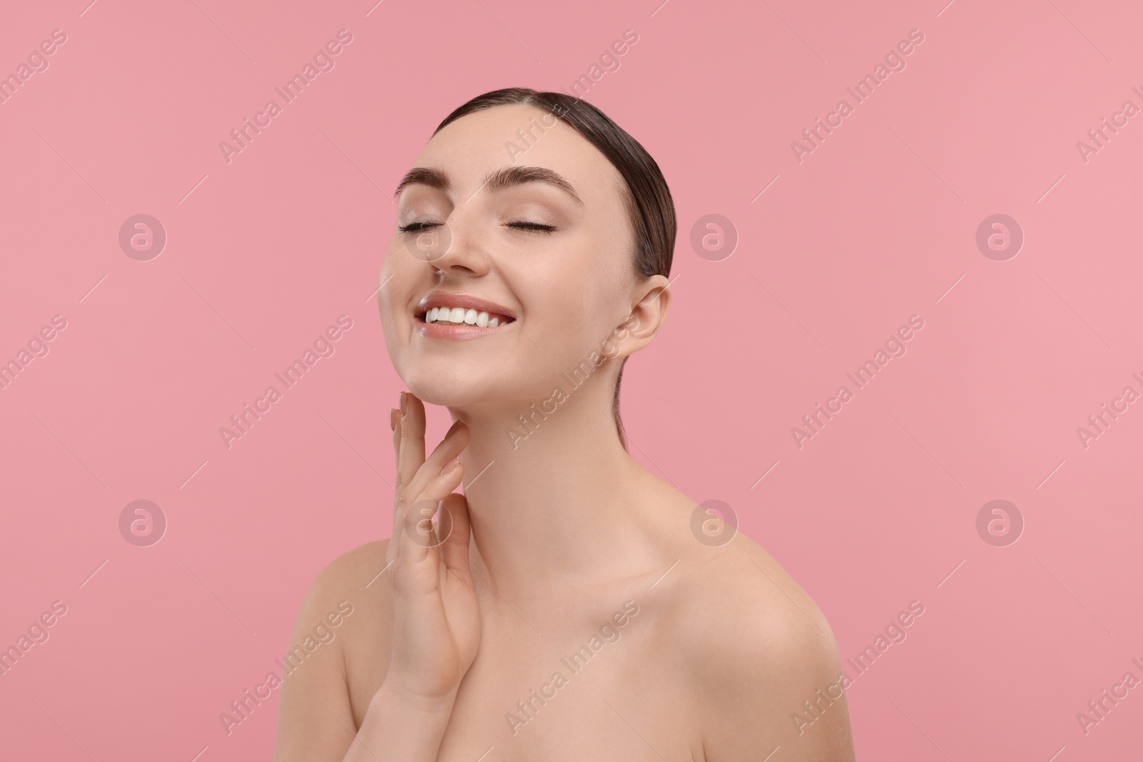 Photo of Smiling woman touching her neck on pink background