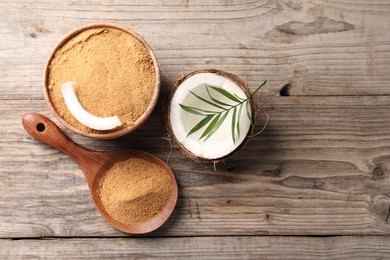 Photo of Coconut sugar in bowl, spoon, palm leaves and fruit on wooden table, flat lay. Space for text