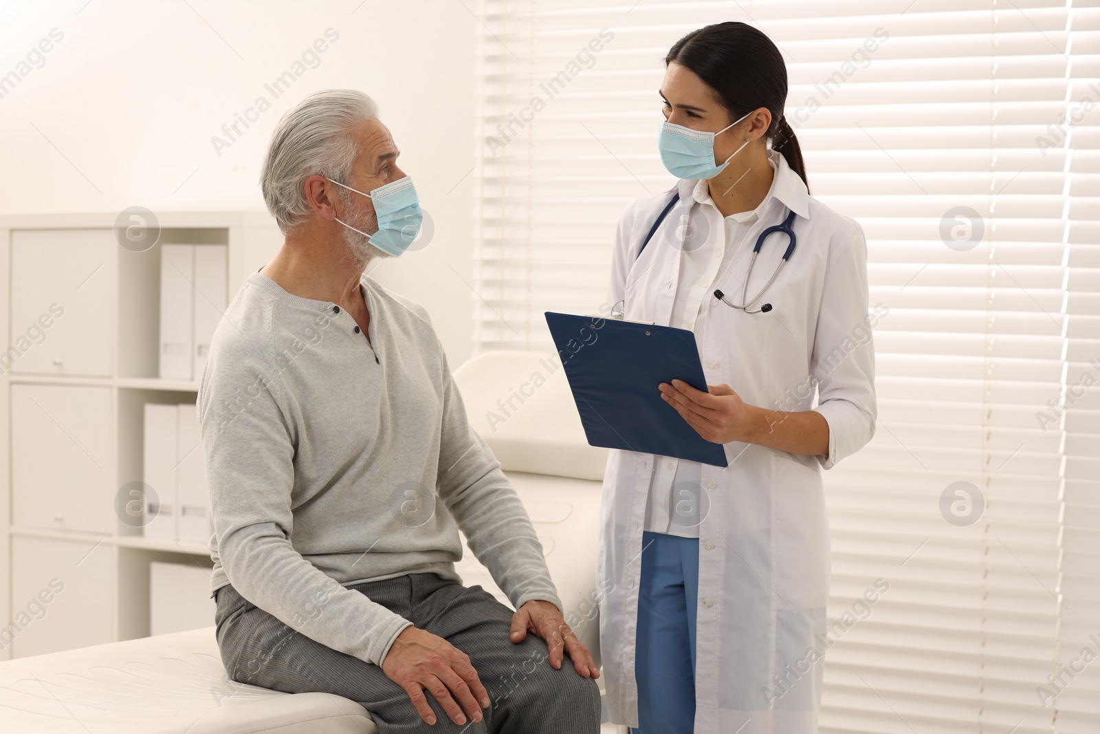 Photo of Nurse with clipboard talking to elderly patient in hospital