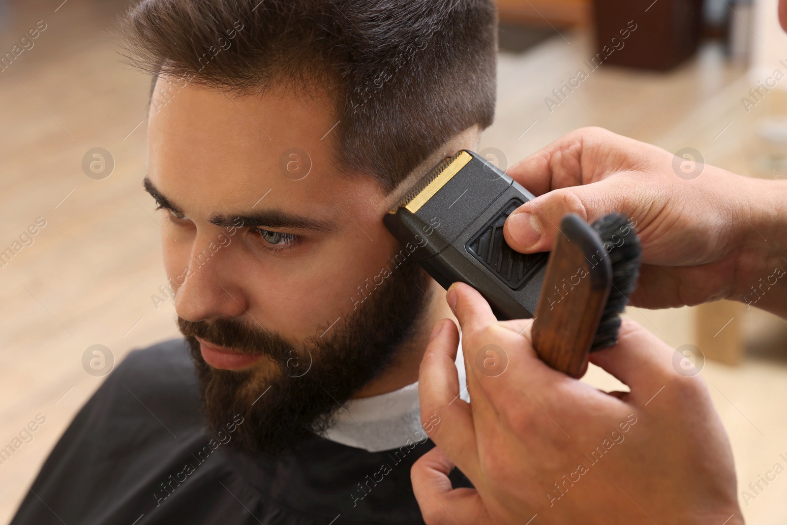 Photo of Professional hairdresser working with client in barbershop, closeup