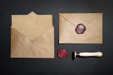 Photo of Envelopes with wax seal and stamp on black background, flat lay