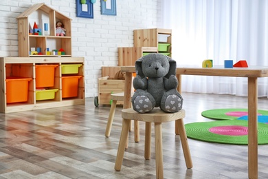 Photo of Stuffed rabbit on stool in child room interior