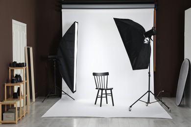 Photo of White photo background, chair and professional lighting equipment in studio