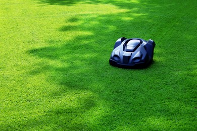 Photo of Modern robot lawn mower on green grass in garden