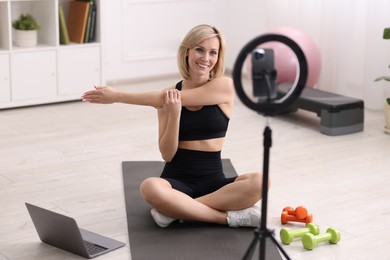 Smiling sports blogger streaming online fitness lesson at home