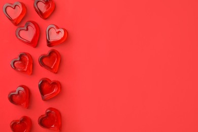 Photo of Many heart shaped jelly candies on red background, flat lay. Space for text