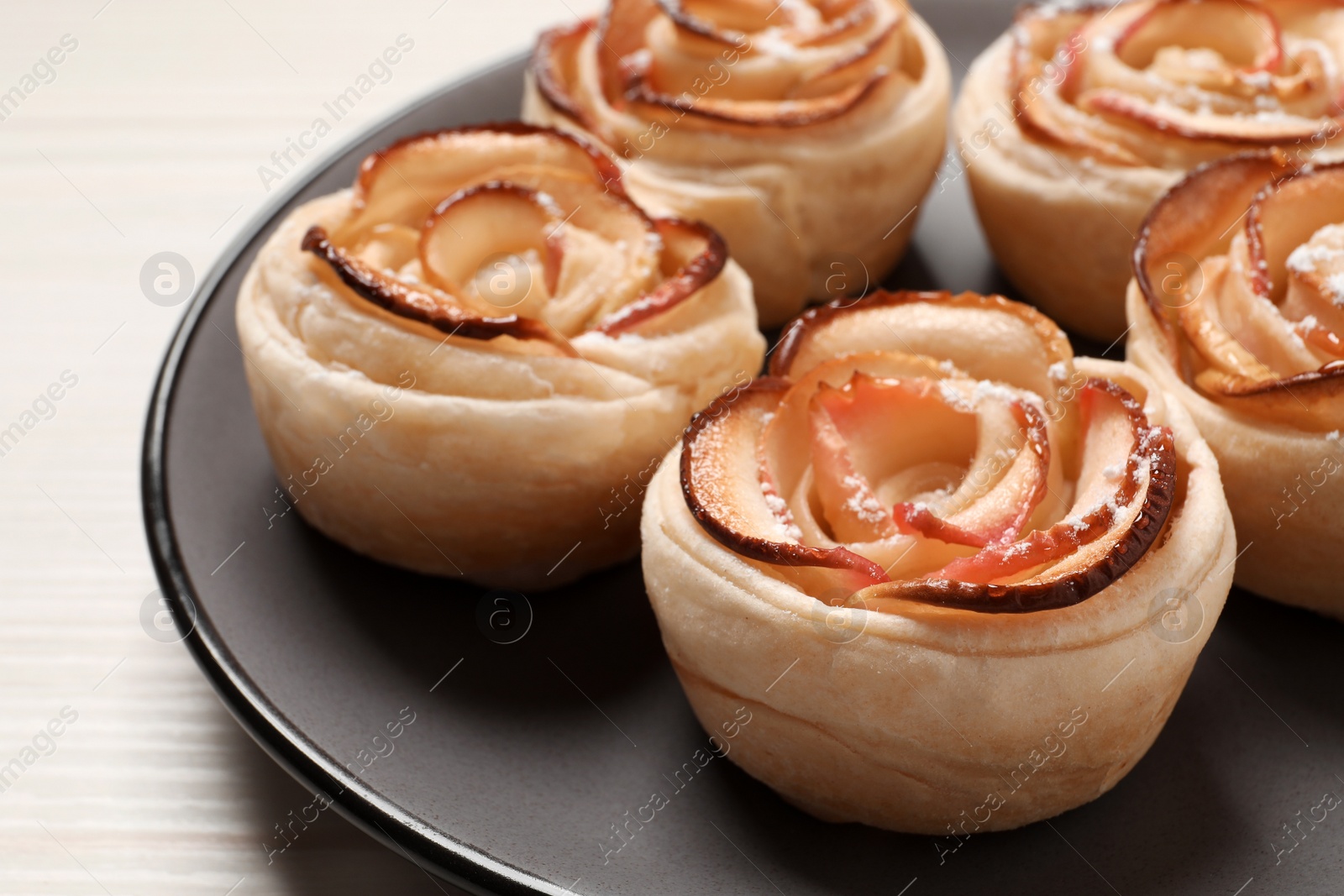 Photo of Freshly baked apple roses on white wooden table. Beautiful dessert