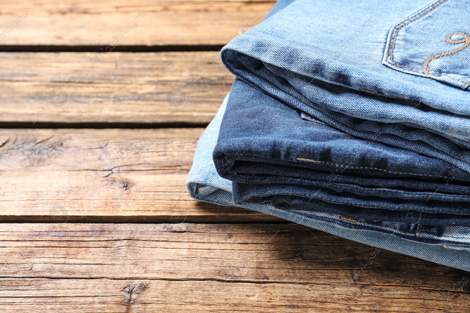 Photo of Collection of stylish jeans on wooden background, closeup. Space for text