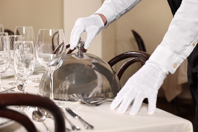 Photo of Man setting table in restaurant, closeup. Professional butler courses