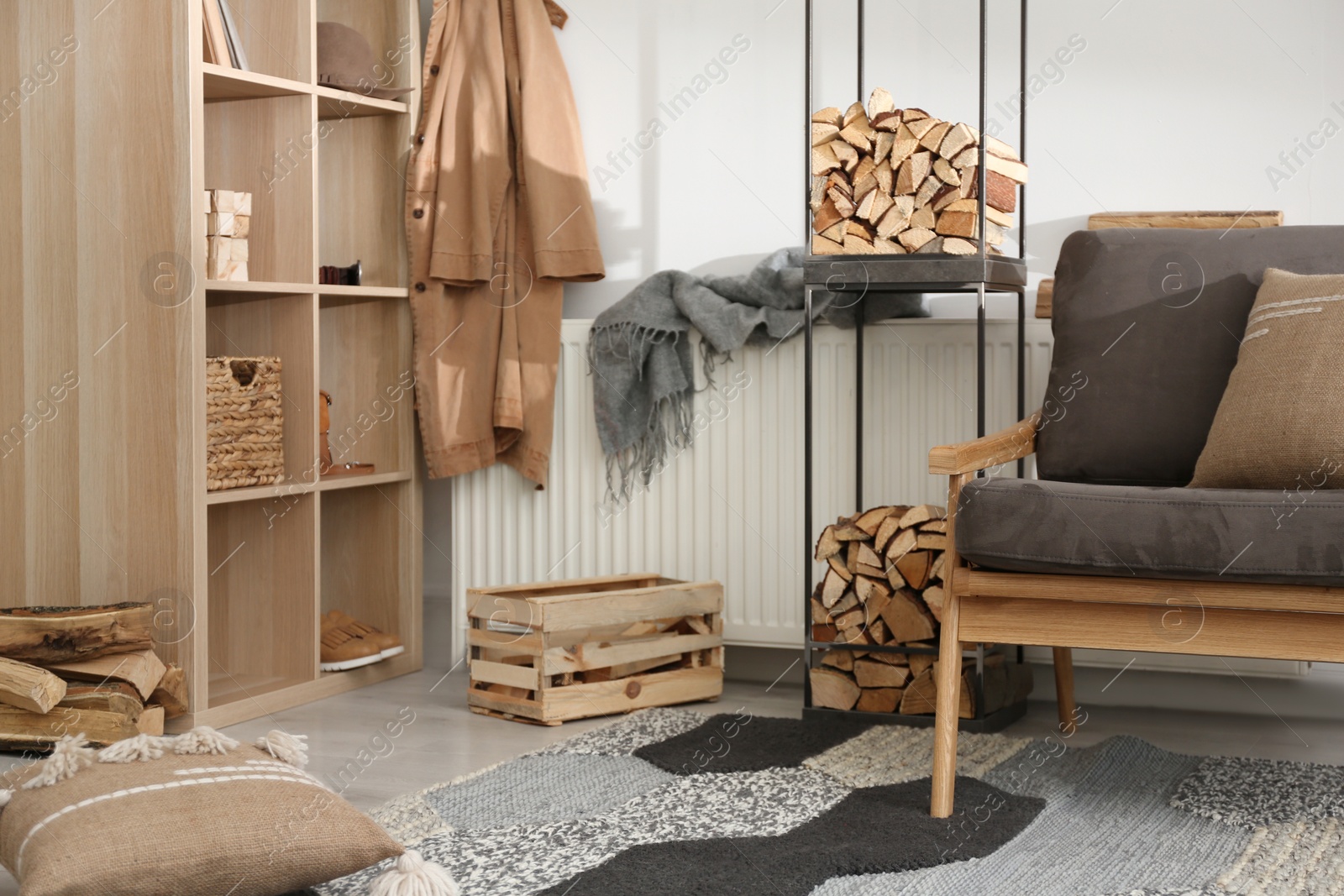 Photo of Firewood near armchair in stylish room interior