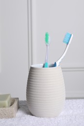 Photo of Plastic toothbrushes in holder and soap bars on towel