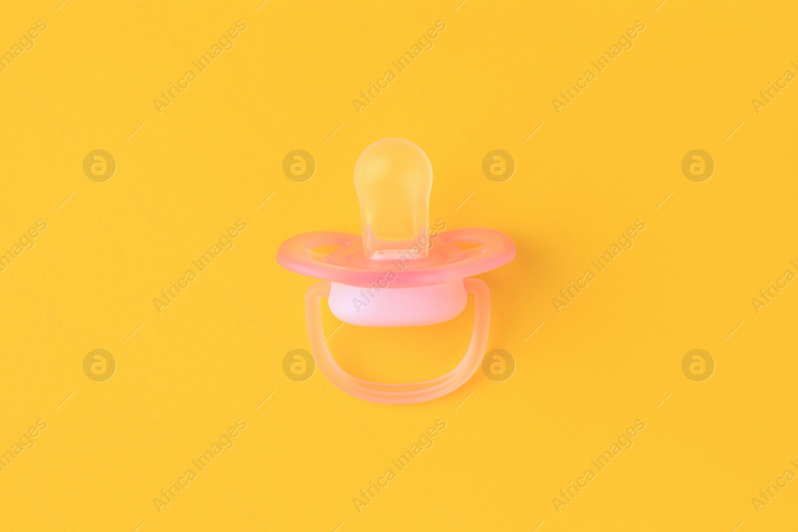 Photo of One new baby pacifier on orange background, top view