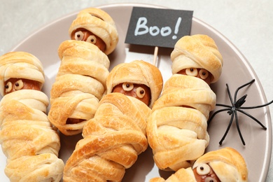 Photo of Spooky sausage mummies on table, closeup. Halloween treat