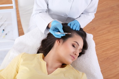 Young woman with hair loss problem receiving injection in salon, top view