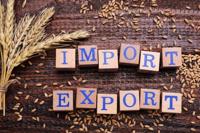 Photo of Words Import and Export made of cubes and wheat on wooden table, flat lay