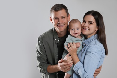 Photo of Happy family. Couple with their cute baby on grey background