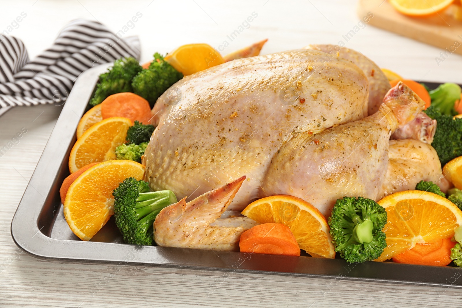 Photo of Raw chicken with oranges and vegetables on white wooden table, closeup