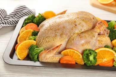 Photo of Raw chicken with oranges and vegetables on white wooden table, closeup