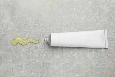 Photo of Open white tube with ointment on light grey table, top view. Space for text