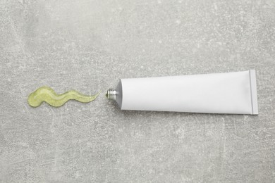 Open white tube with ointment on light grey table, top view. Space for text